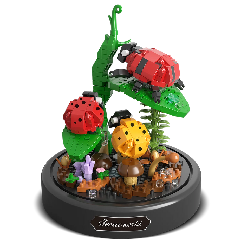 Produktfoto der Balody Miniblocks zwei rote und ein gelber Marienkäfer auf einem Stiel mit Blättern und Pilzen auf dem Boden, unter einer Glocke