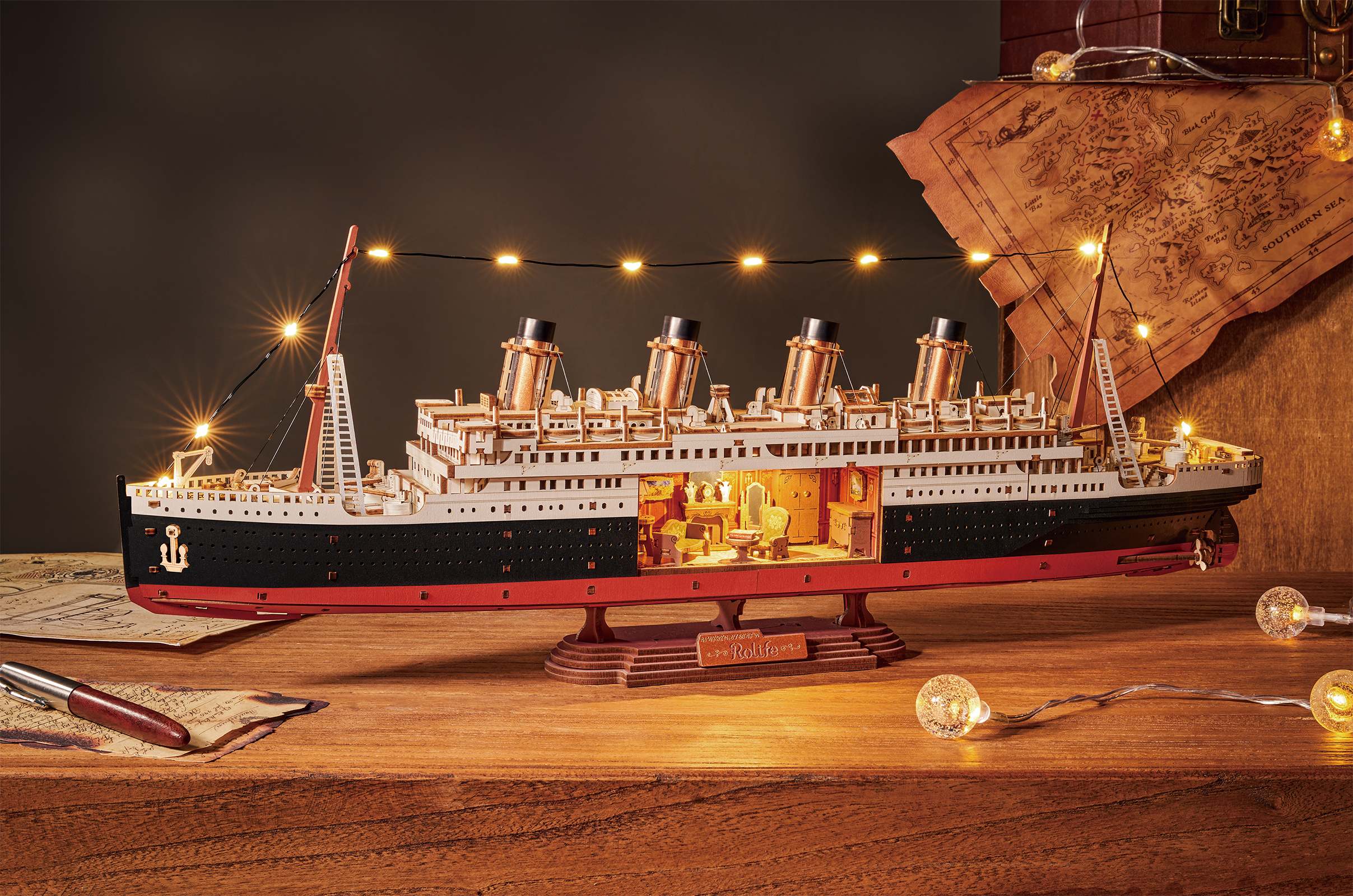 Atmosphärische Präsentation der Robotime 1912 - Eternal Atlantic Voyager, Holzmodellbau eines Vintage-Dampfschiffs mit einem Ausschnitt im Rumpf, durch den man Retro-Interieur sehen kann