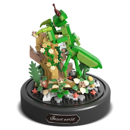 Produktfoto der Balody Miniblocks Gottesanbeterin auf einem Zweig mit Blumen und pflanzlichem Boden, unter einer Glocke
