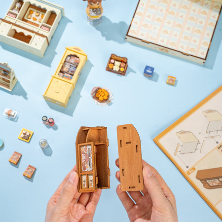 Eine Person baut die Ladentheke des Robotime Cookii Bunny’s Cookie Shop