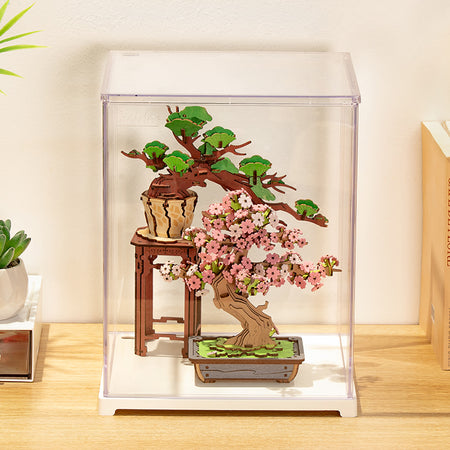 Die Robotime Staubschutzhülle Portrait M mit darin enthaltenem Robotime Sakura Bonsai und Evergreen Pine Bonsai