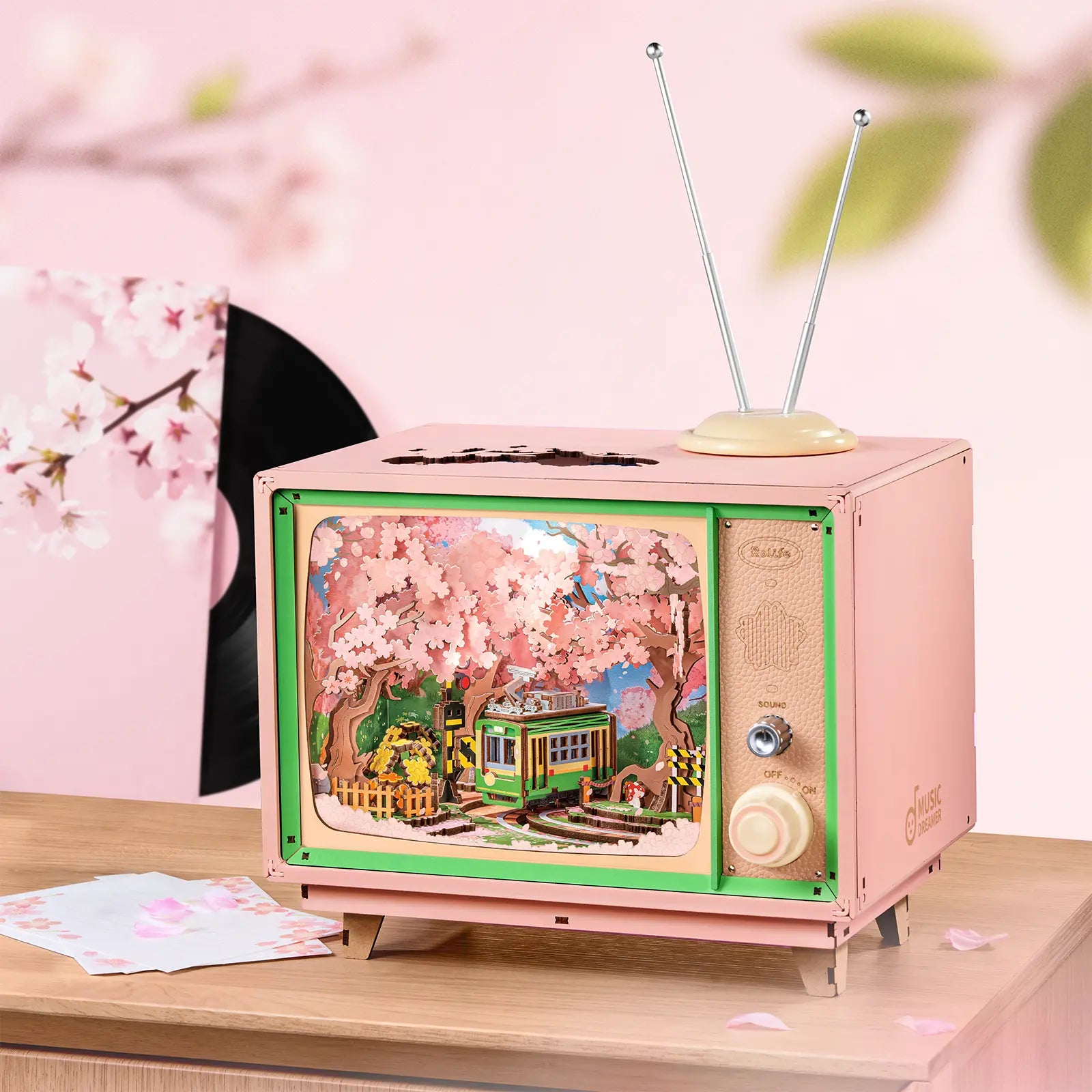 Atmosphärische Präsentation der Robotime Sakura Dreamy Tour, Holzbausatz eines Fernsehgeräts mit einer herumfahrenden Straßenbahn